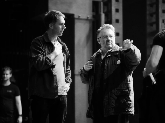 Black and white: director Leo Warner in conversation with a cast member during rehearsals.