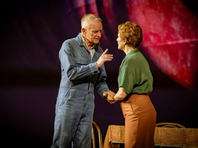 Jackie and Peggy White hold hands mid-argument beside a cloth-covered table.