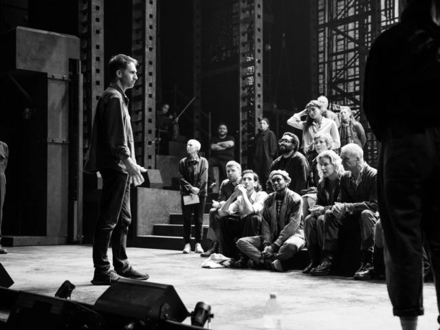 Black and white: Leo Warner addresses the seated company from the front of the stage.